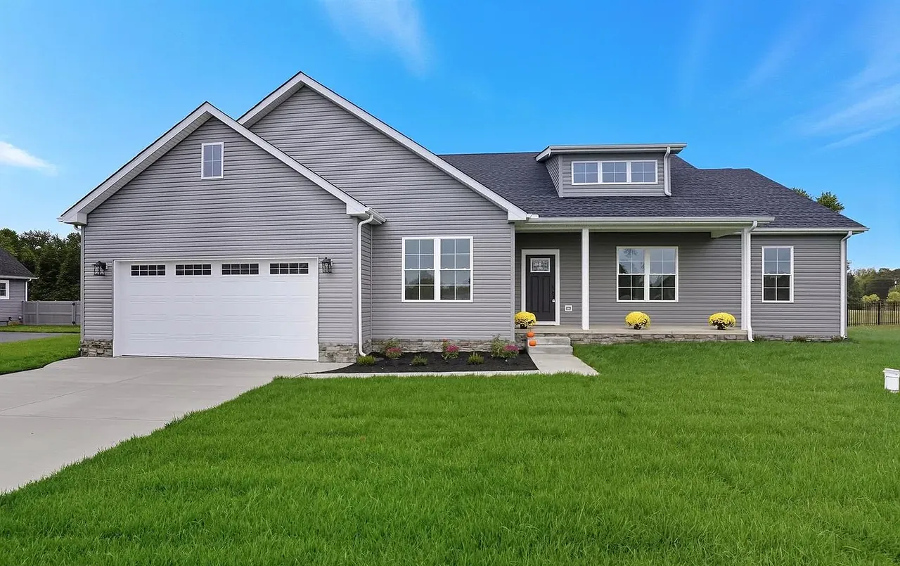 Grey craftsman-style new build with attached two-car garage and manicured lawn