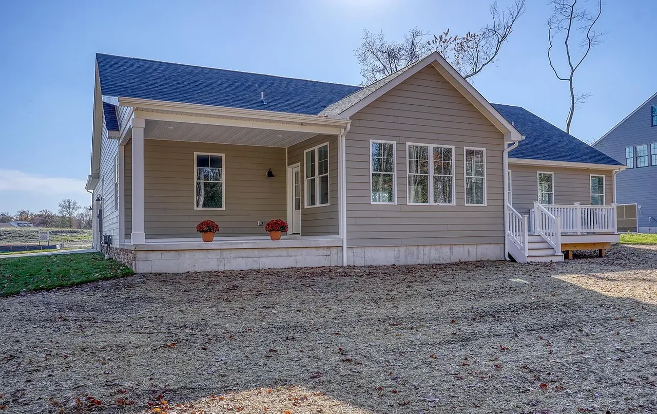 Tan ranch home with full-width covered porch nearing completion